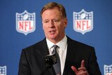 An NFL executive stands in front of a microphone speaking at a press conference.