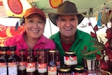 Two people sitting at a stall selling rosella products.