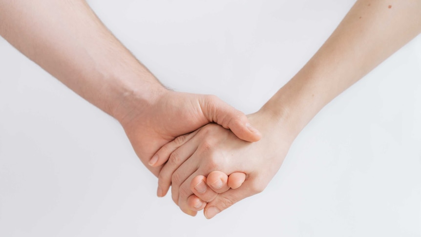 Two people holding hands on a white background