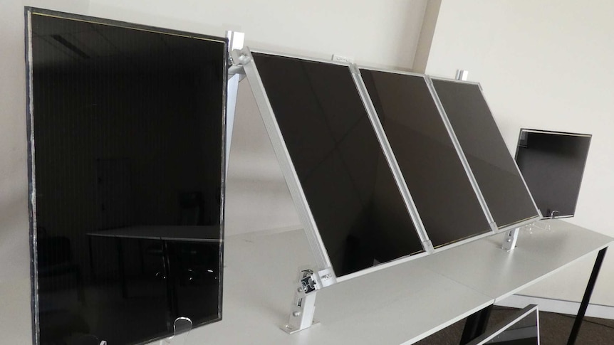 Mini Perovskite solar panel prototypes, similar in look to a small flat screen tv, sitting on a desk