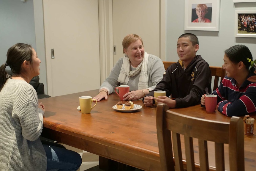 Kerryn Longmuir laughs while having tea at the table with three siblings