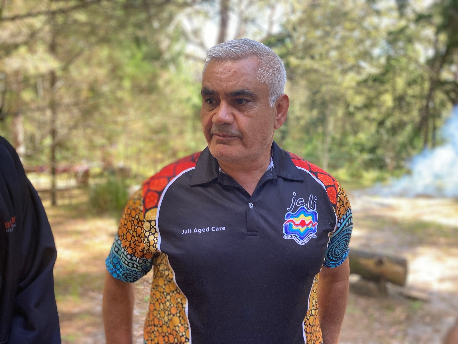 Grey-haired man in short with indigenous print.