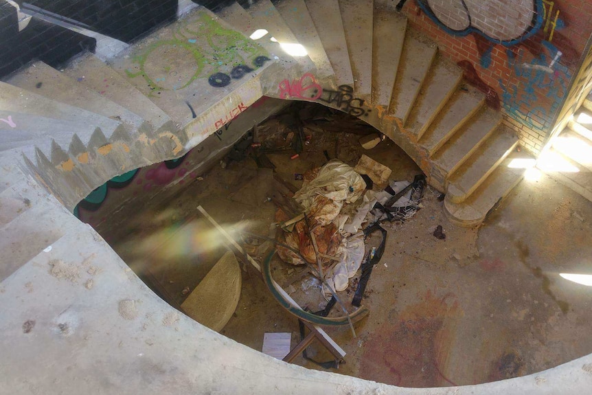 An unfinished concrete staircase with graffiti and a pile of rubbish.