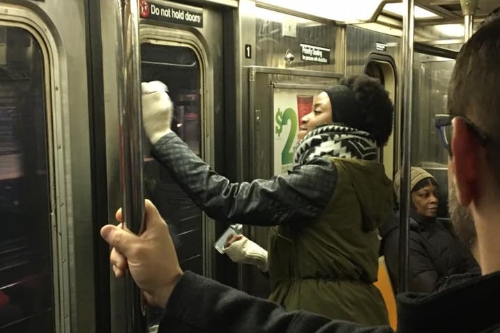 Woman joins other commuters and cleans swastika symbols and racist messages off subway window and wall in New York.