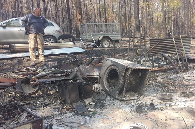 A man looks over a pile of burnt household goods