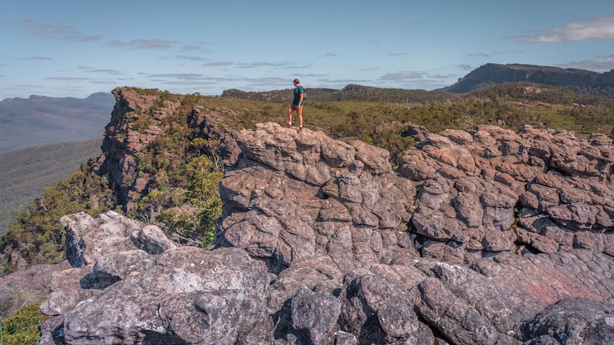 A hiker stands on a mountain range.