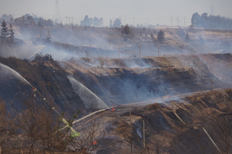 An image from inside the open-cut coal mine shows sprinklers dousing smoking coal walls.