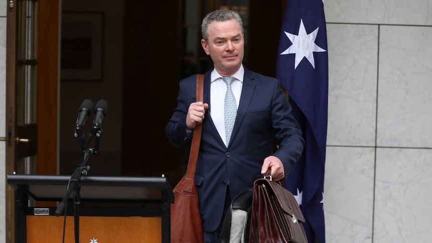 Christopher Pyne walks past the site of Malcolm Turnbull's final press conference as PM, carrying a bag and briefcase.