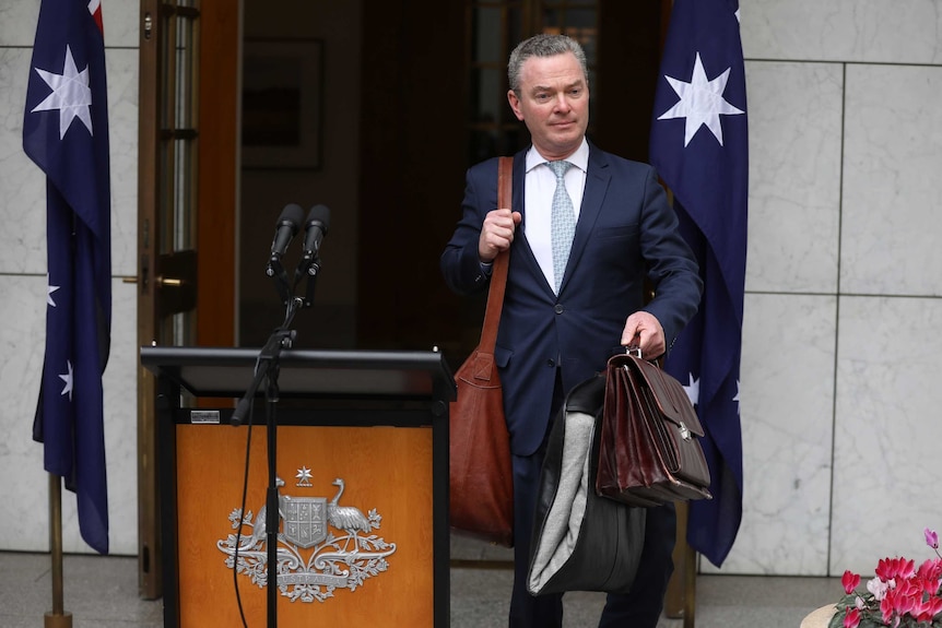 Chrisopher Pyne walks past the site of Malcolm Turnbull's final press conference as PM, carrying a bag and briefcase.