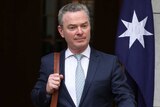 Christopher Pyne walks past the site of Malcolm Turnbull's final press conference as PM, carrying a bag and briefcase.