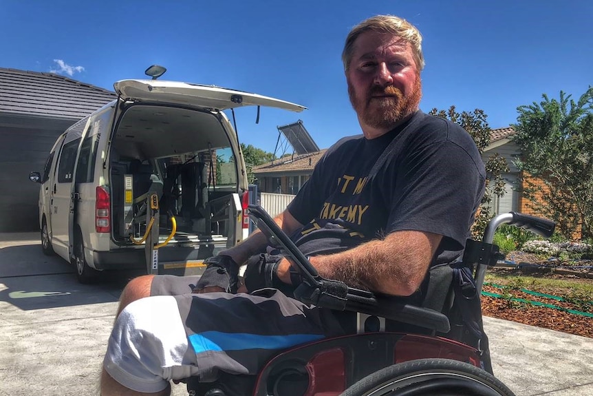 Mick Higgins sits in his wheelchair in a driveway.