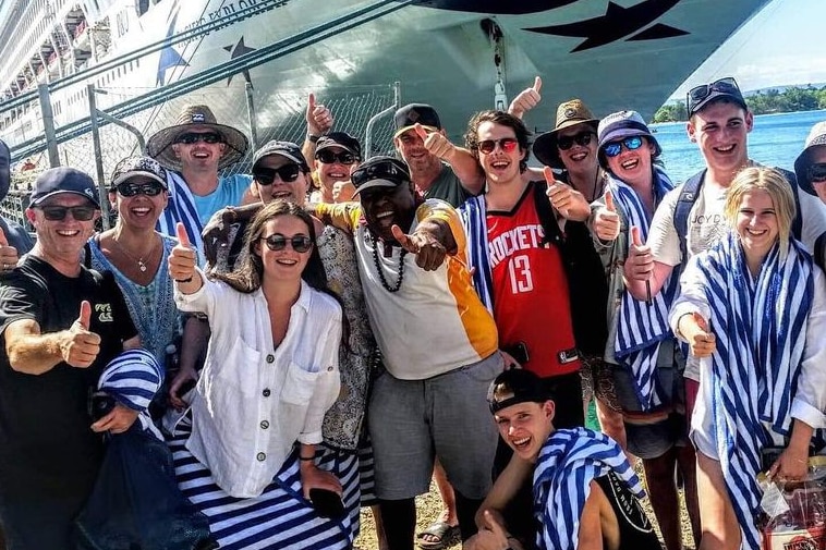 A group of tourists in front of a large boat with their ni-Vanuatu tour guide