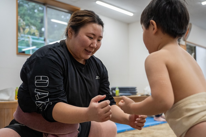 A woman squats in front of a small boy 