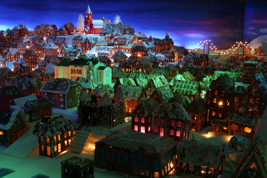 Model houses and blocks of flats made of gingerbread sit on a rising hill that leads to a gingerbread church.