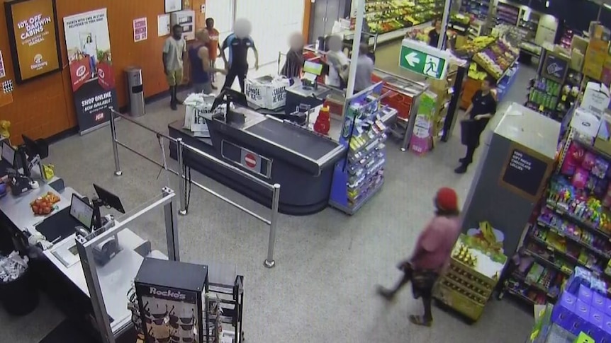 CCTV vision shows people milling about a checkout at a supermarket.