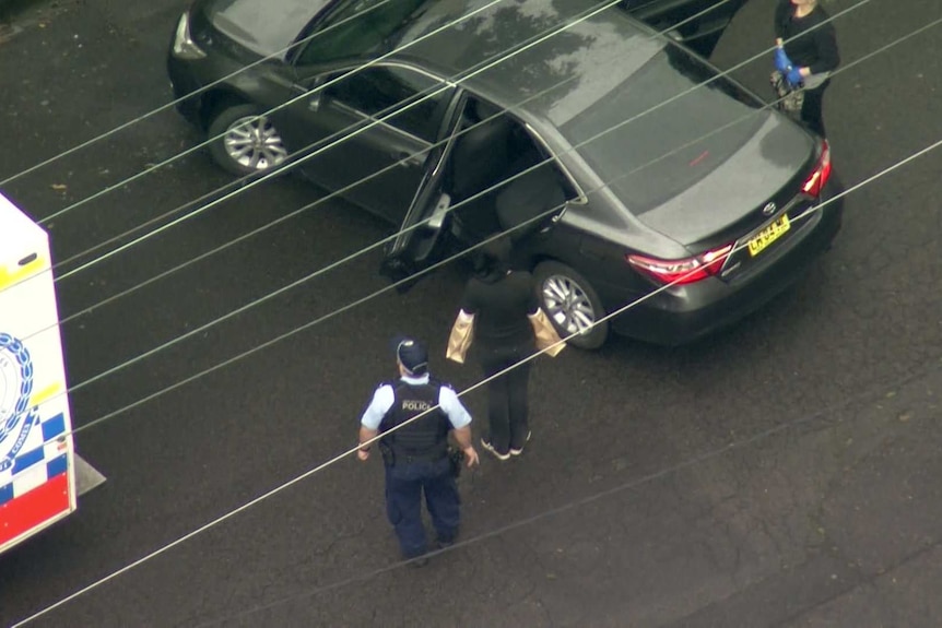 A woman walking towards a car seen from above.