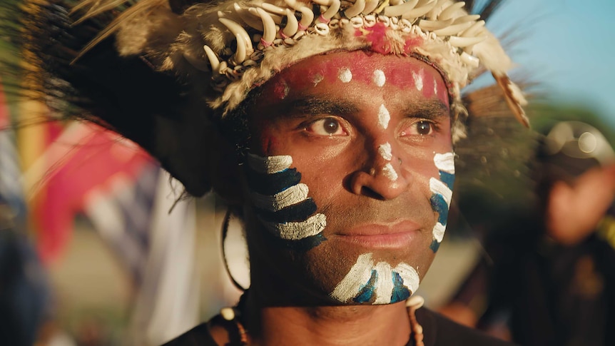 A man's face painted blue, white and red.