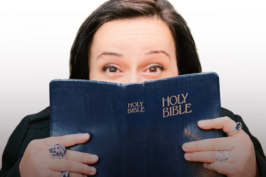 A woman holds up a bible over her face