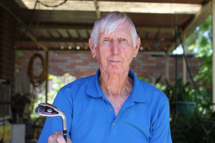 kevin sitting in shed holding golf club