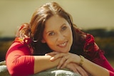 A photo of Margaret Ulrich in a red top smiling at the camera