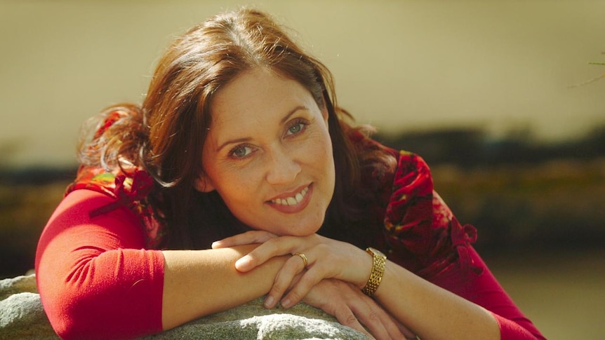 A photo of Margaret Ulrich in a red top smiling at the camera
