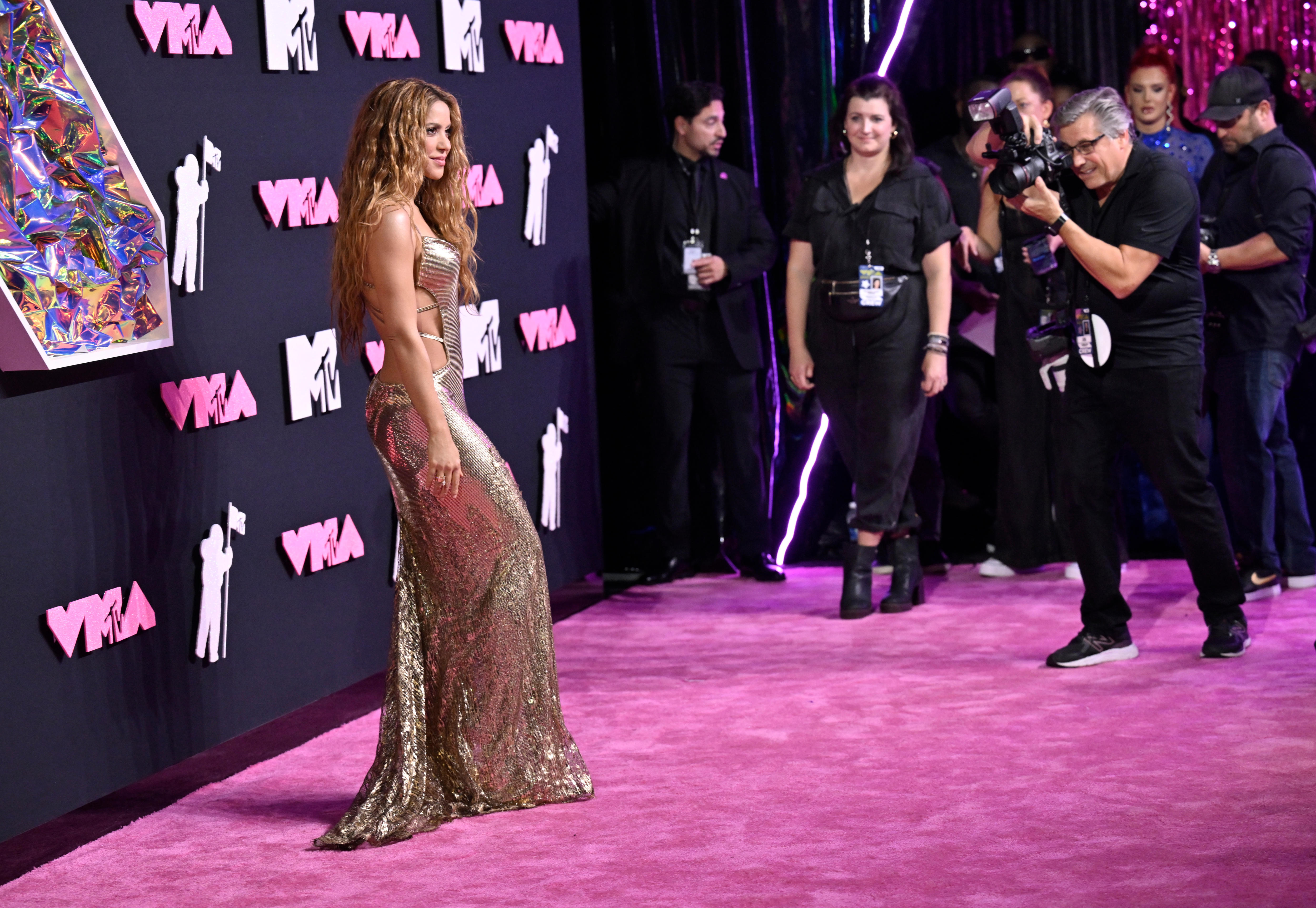 Shakira stands on pink carpet posing for photographers