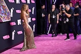 Shakira stands on pink carpet posing for photographers