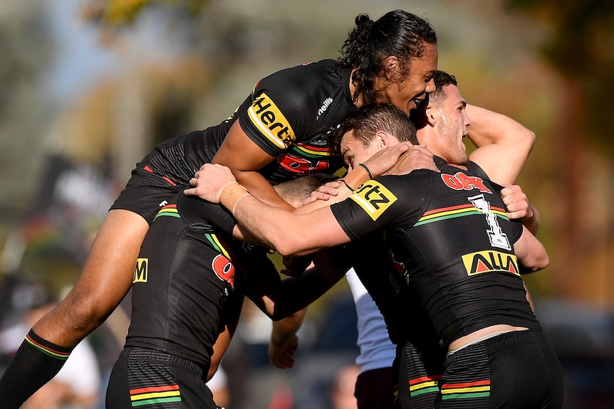 Jarome Luai jumps on top of his Penrith Panthers teammates, including Dylan Edwards and Nathan Cleary.
