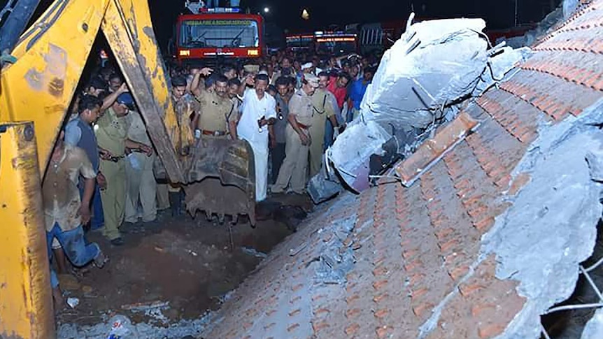 Indian officials and bystanders gather at the scene of a deadly temple fire in Kerala