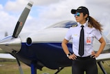Li Zhuang stands in front of a small plane, hands on hips, in her pilot's uniform.