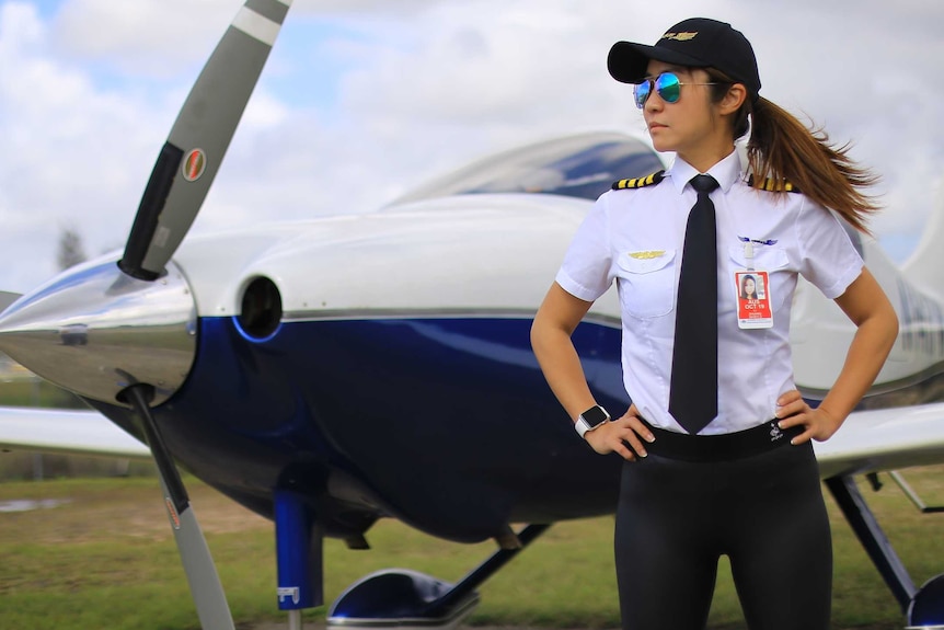 Li Zhuang stands in front of a small plane, hands on hips, in her pilot's uniform.
