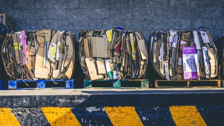 folded up cardboard boxes lying on three crates against dark grey brick wall