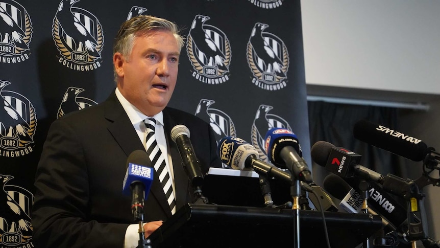 Eddie McGuire debout à un pupitre devant une bannière avec le logo des pies.