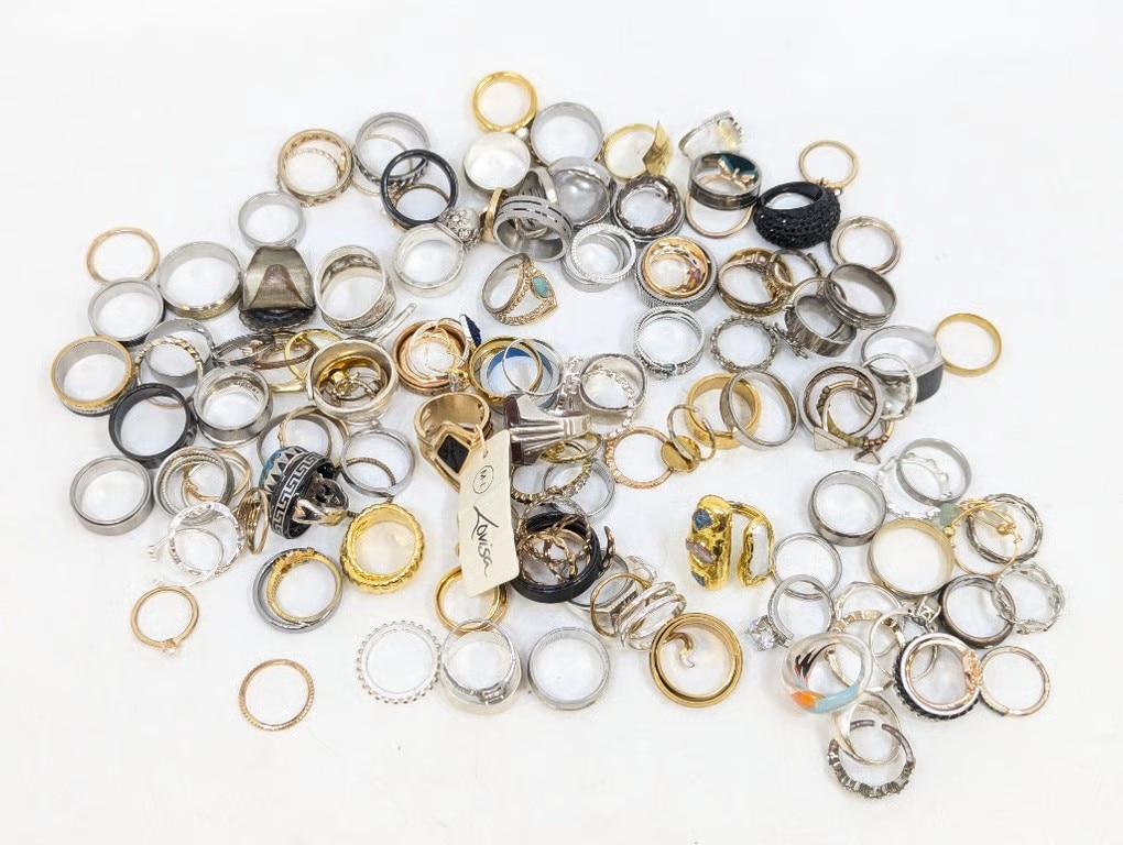 Uma mesa cheia de anéis de ouro e prata sobre a mesa.