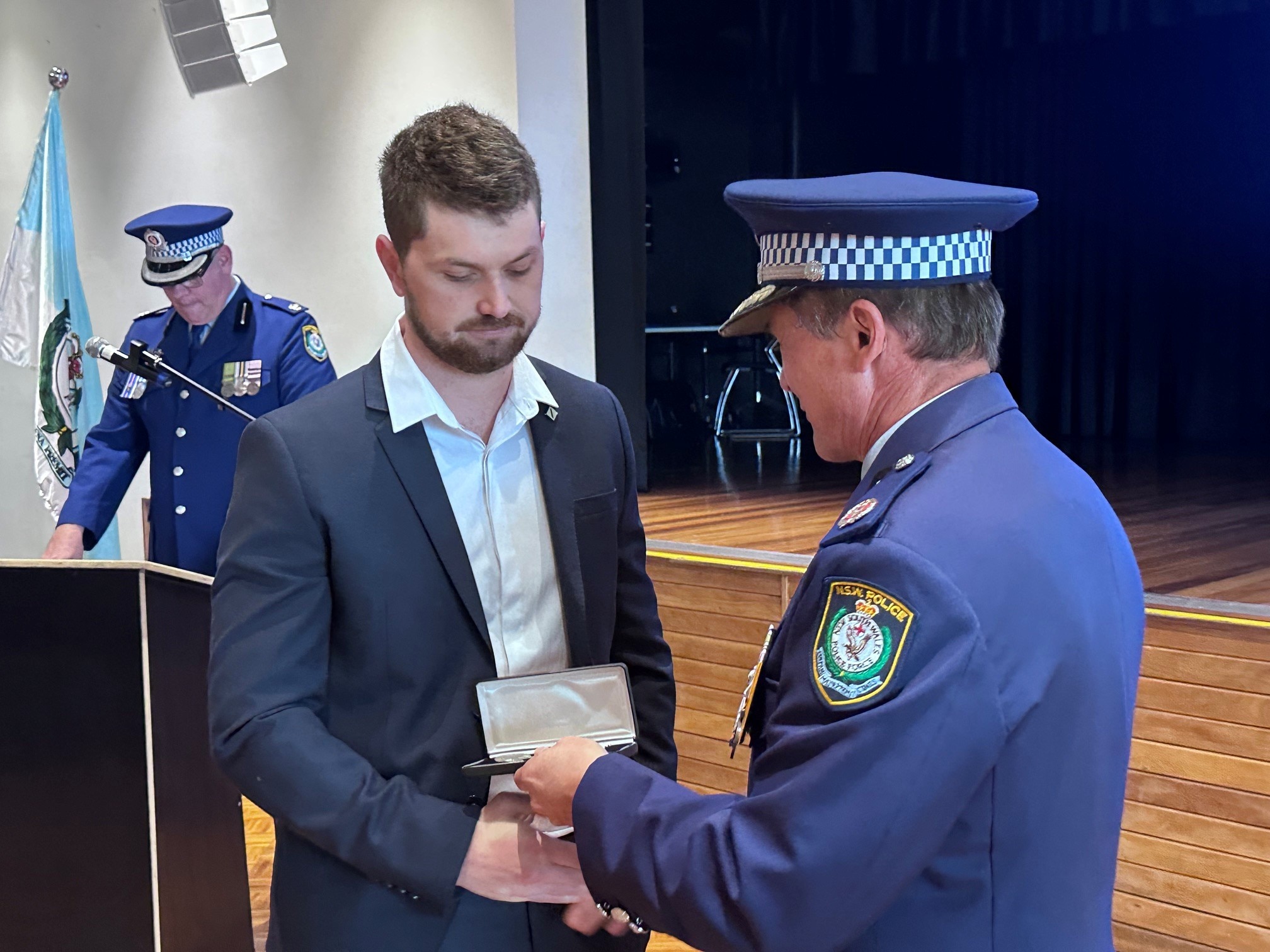 A young man is handed an award by a police officer