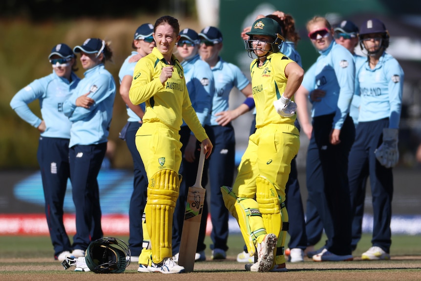 Australia batters Rachael Haynes and Alyssa Healy lean on their bats as the England team stands behind them during an ODI.