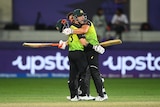 Matthew Wade and Marcus Stoinis pictured hugging and celebrating in the middle of a cricket ground.