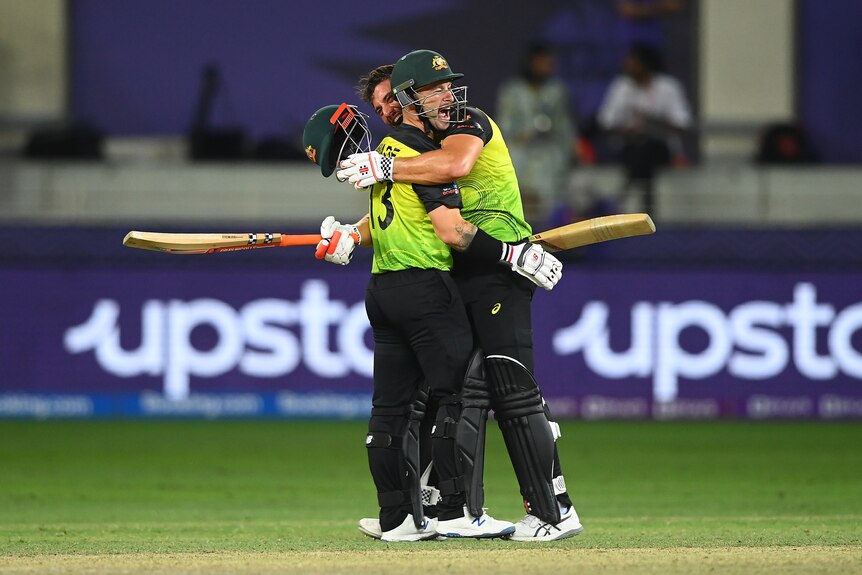 Matthew Wade and Marcus Stoinis pictured hugging and celebrating in the middle of a cricket ground.