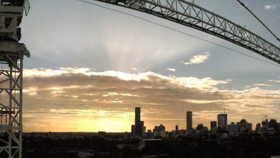 The sun sets over a construction site in Brisbane city.