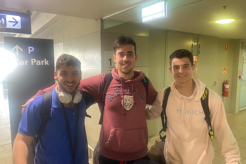 Three dark haired young men at airport