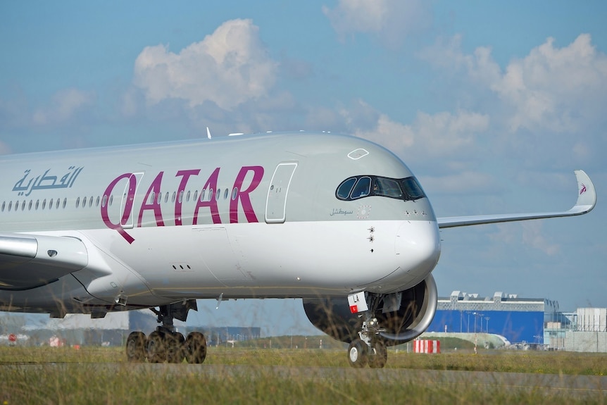 A Qatar Airways Airbus A350-900 on the tarmac on a lightly cloudy day.