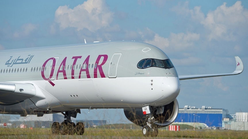 A Qatar Airways Airbus A350-900 on the tarmac on a lightly cloudy day.