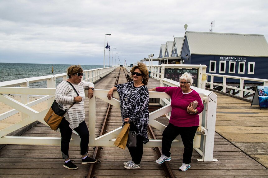 Three women at the entrance to a timber jetty.