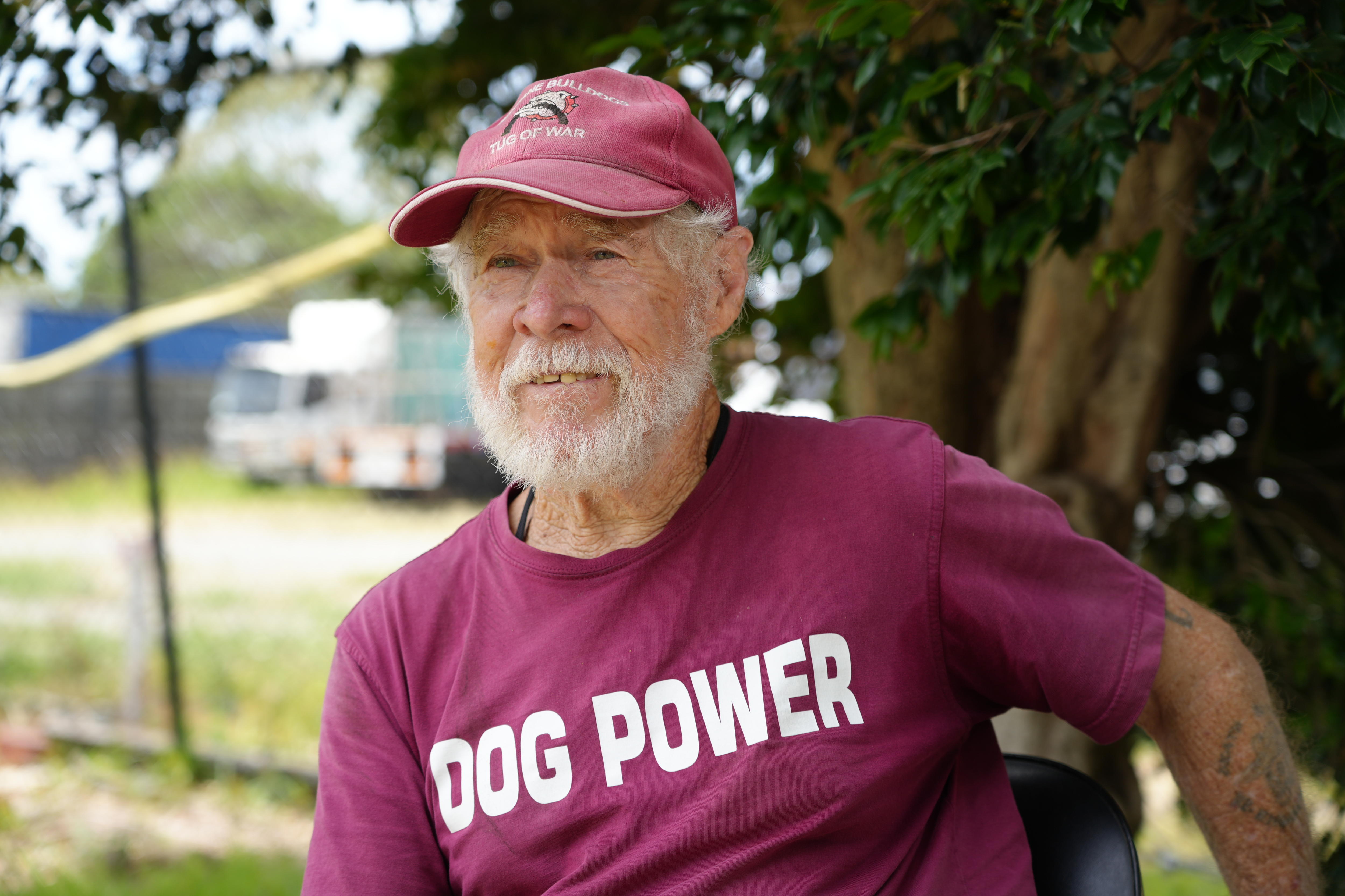 Um homem com um boné marrom e uma camisa marrom onde se lê “poder do cão”.