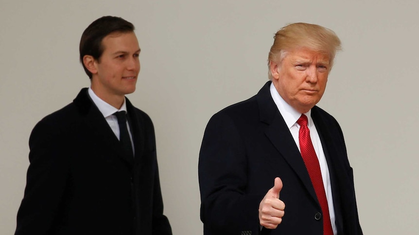 Donald Trump walks ahead of Jared Kushner and gives a thumbs-up sign.