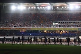 The silhouettes of players can be seen at a dark Gabba