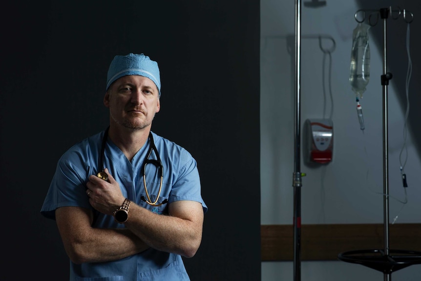 A doctor looking serious and standing inside a hospital room