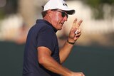 Phil Mickelson waves to the crowd while holding his golf ball