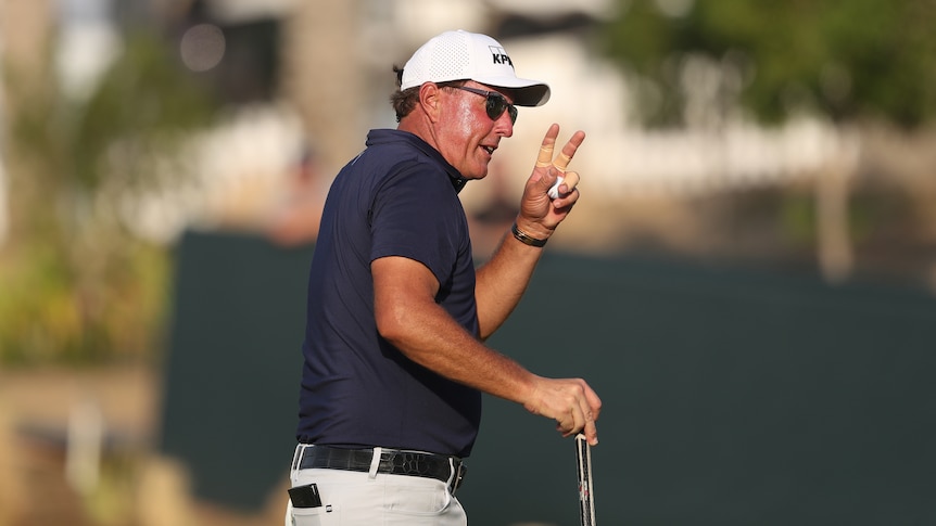 Phil Mickelson waves to the crowd while holding his golf ball