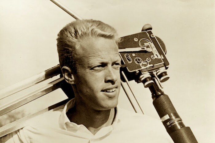 Brown slings his camera over his arm during filming of the endless summer - black and white image